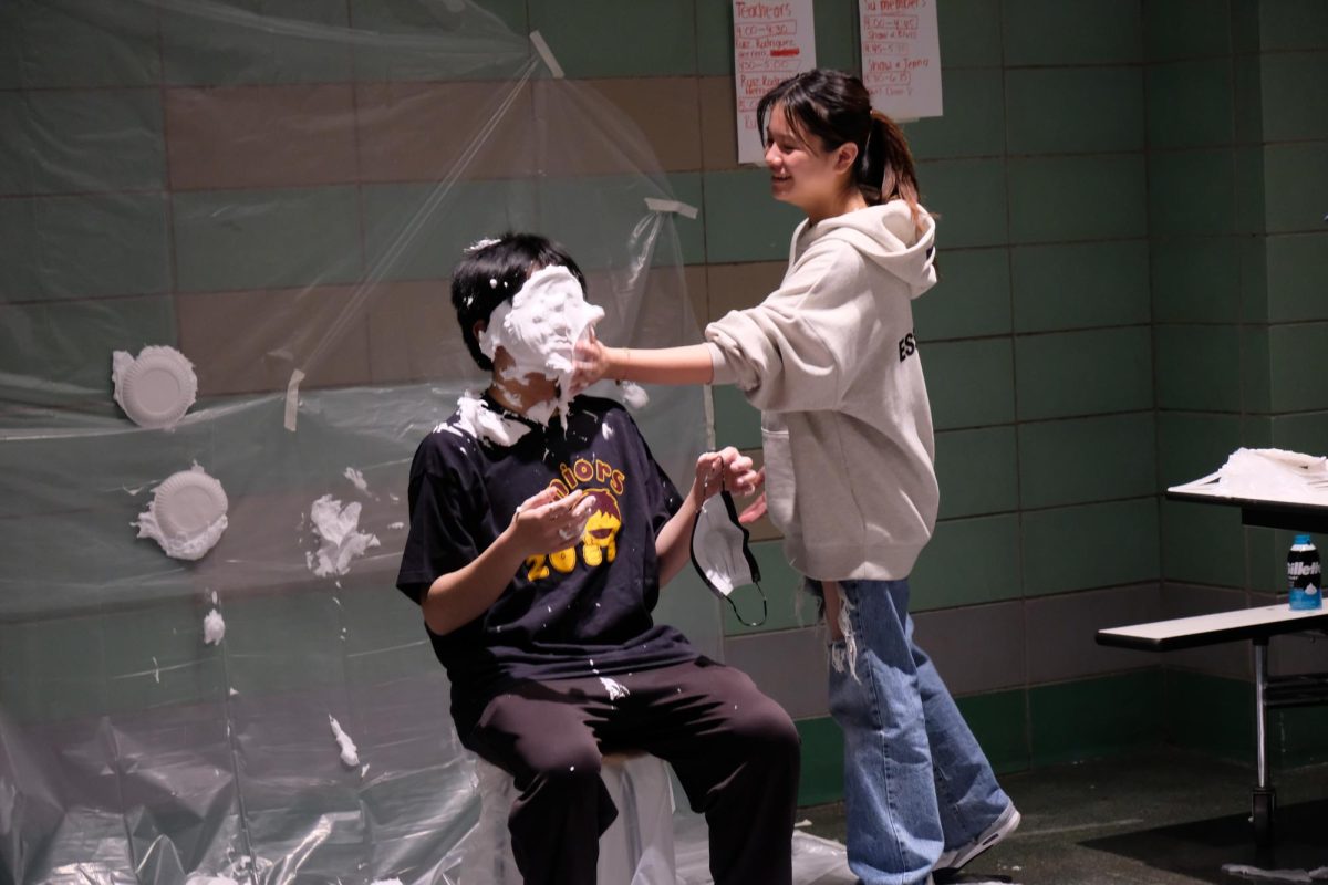A student getting pied at the Sophomore Grade Leaders booth at Winter Carnival.