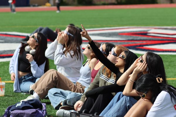 Students assemble at the QC track to look at the solar eclipse through protective glasses. 