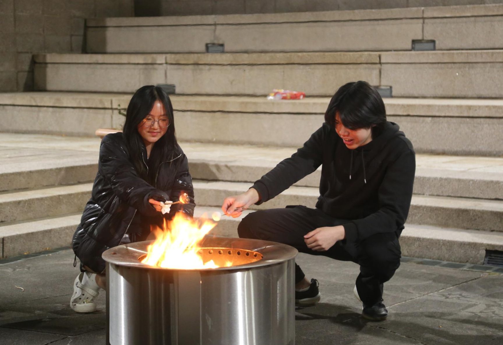 Students by the fire in the courtyard at the Witching Hour. As the sun rose, students in the courtyard listened to an excerpt from Stephen King's scary stories.