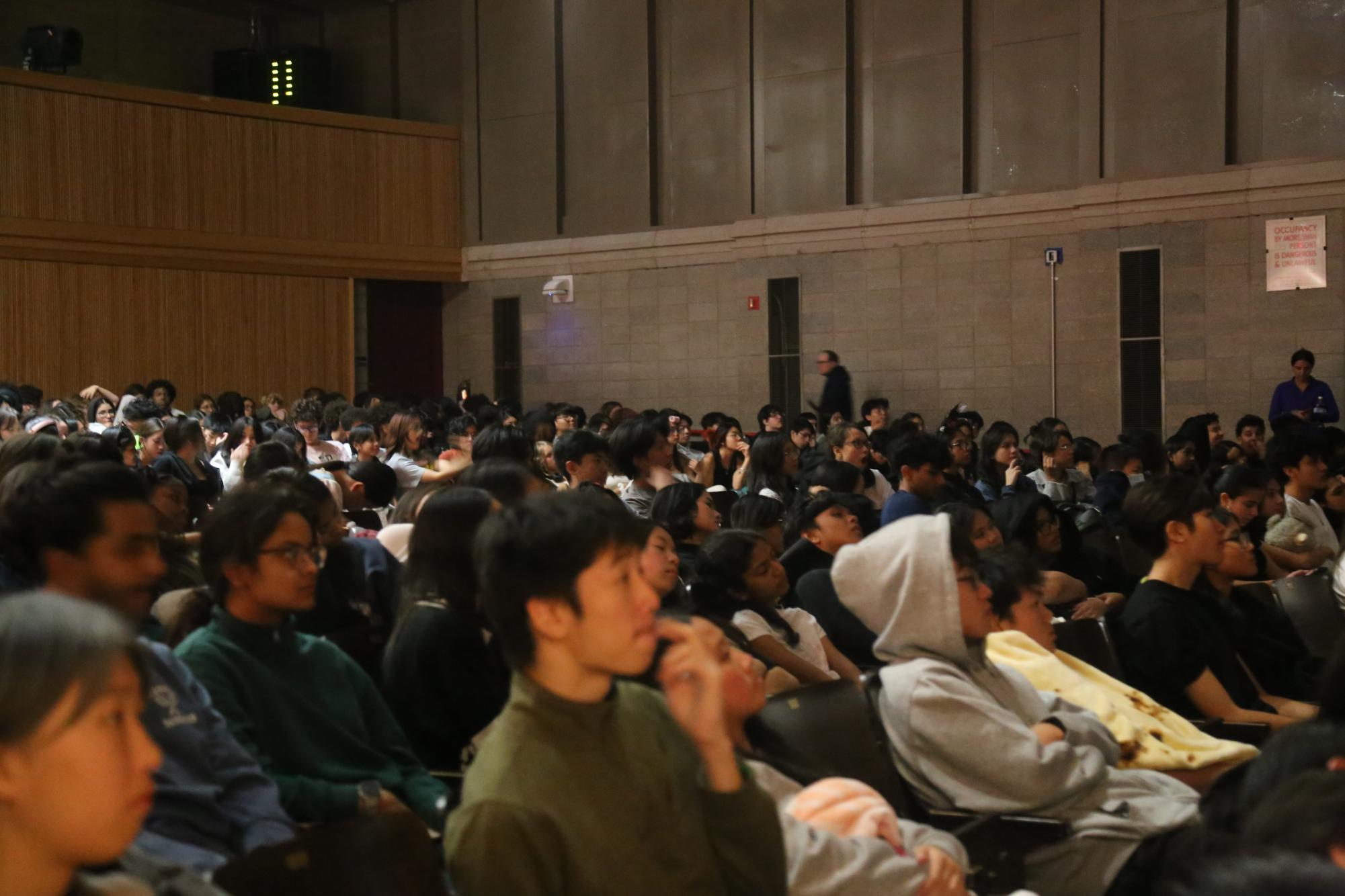 Students listening to readings from Edgar Allen Poe's classic stories at midnight in the auditorium.