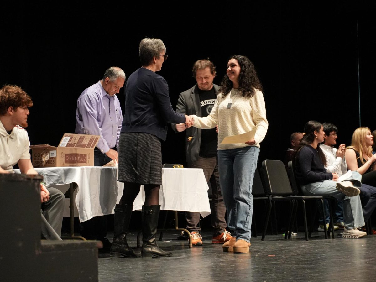 Assistant Principal of Organization Ms. Fee shaking hands with new inductees of the Archon Honor Society