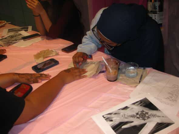 MSA member drawing a henna design on a participant's hand. 