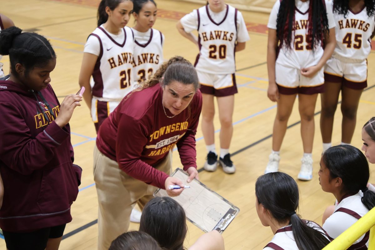 Coach Caiaccia leads a team huddle during timeout at a girls varsity basketball game. 