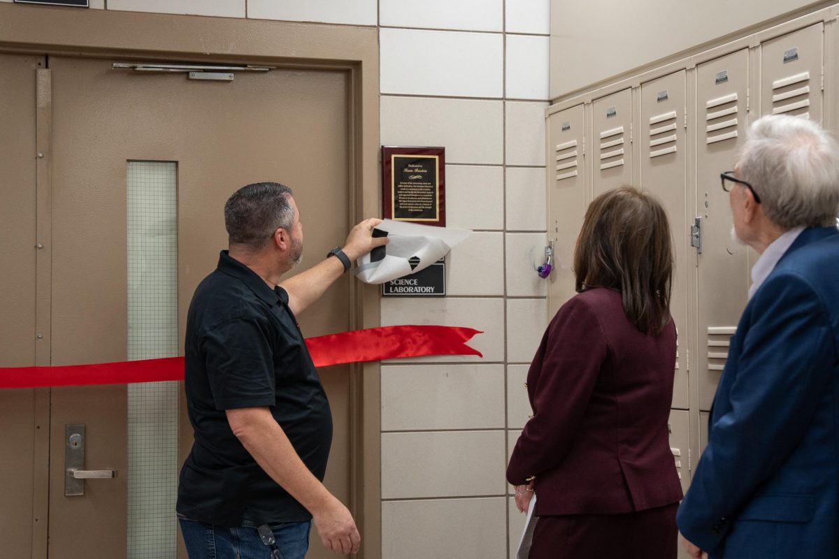 Science teacher Joel Heitman revealing a plaque dedicated to former Assistant Principal of STEM Susan Brustein, and renaming a chemistry lab in her honor.
