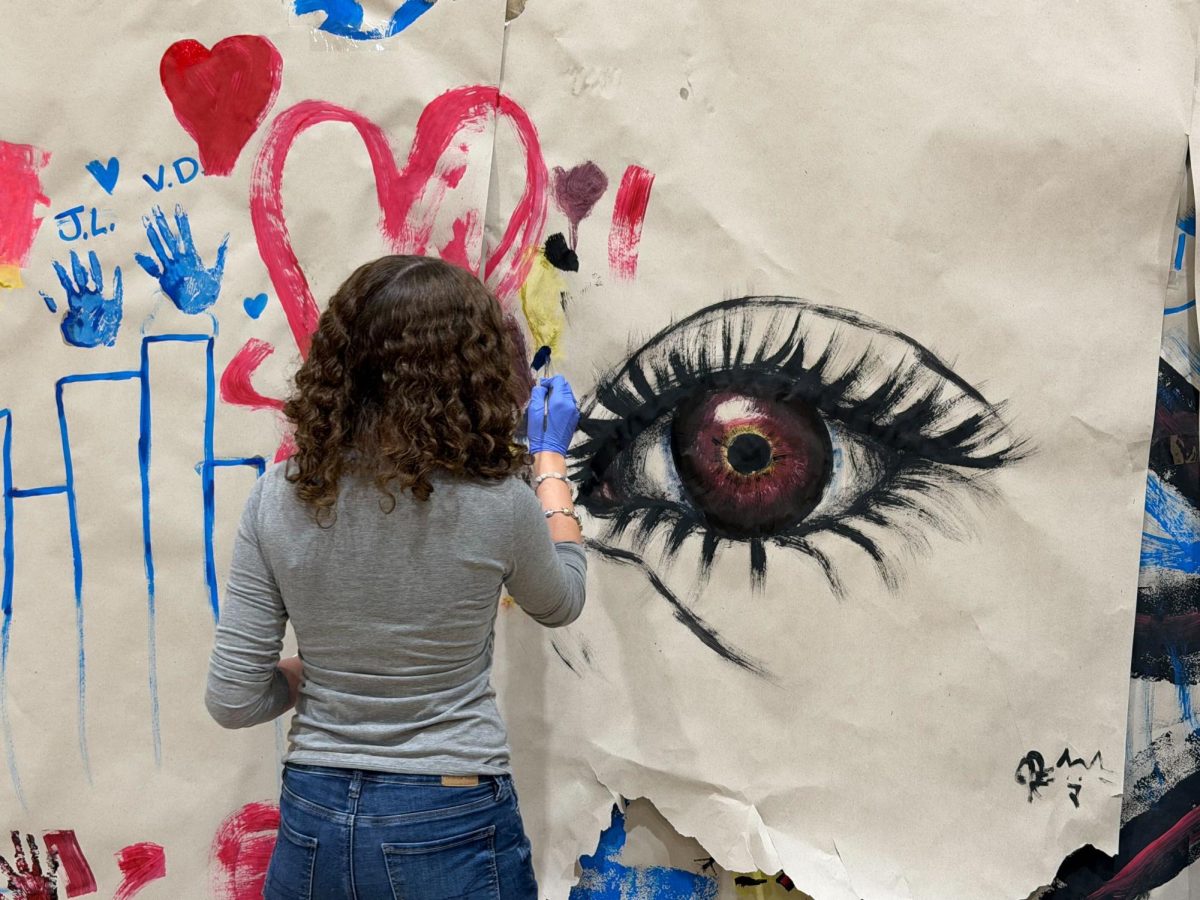 A student during the PE heART initiative painting a detailed eye with a red iris on January 9.