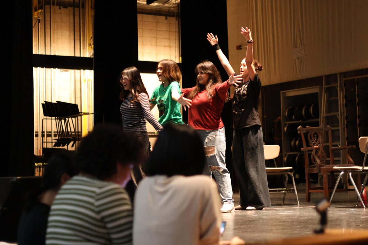 Sophomores Clair Kim, Lilly Chase, Annabelle Clow, and junior Sophia Cherry practicing their song during the runthrough for Act I while stage crew oversees them.
“I would say the most difficult part of my role is the singing that it requires because it's unlike anything I've ever done,” said Lilly, who plays the role of Rusty. “But I feel like I've grown a lot as a vocalist throughout my time playing this role.”
