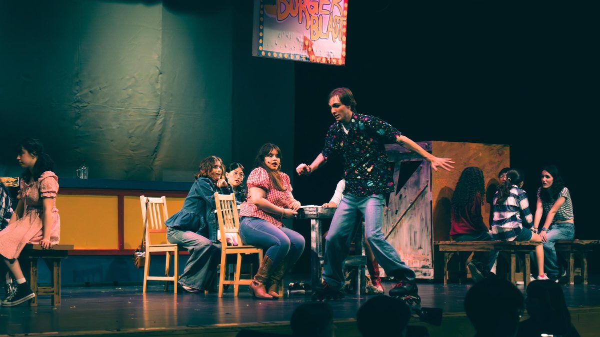 Junior Lukas Cooper, who played the lead role of Ren McCormack, skating across the stage during the Burger Blast scene within the Nightingale Spring Musical of “Footloose”
