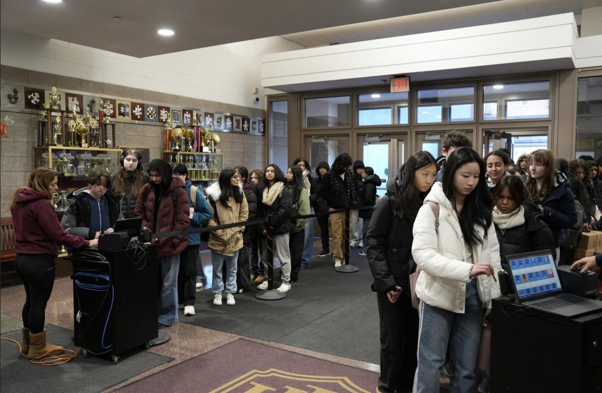Students line up to scan their IDs after the introduction of an ID scanning system. Afarah Cruz-Tillery states that the system has caused occasional delays. Afarah believes that when the system's delays cause students to be late, students should not be marked late.