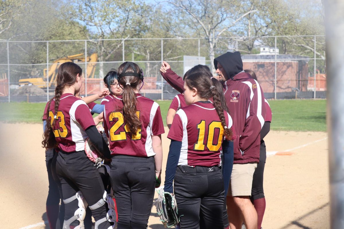 Coach Daniel Largana doing a team huddle during the girls varsity softball game on April 20 against Young Women’s Leadership School, which THHS won with a score of 16-2. 
