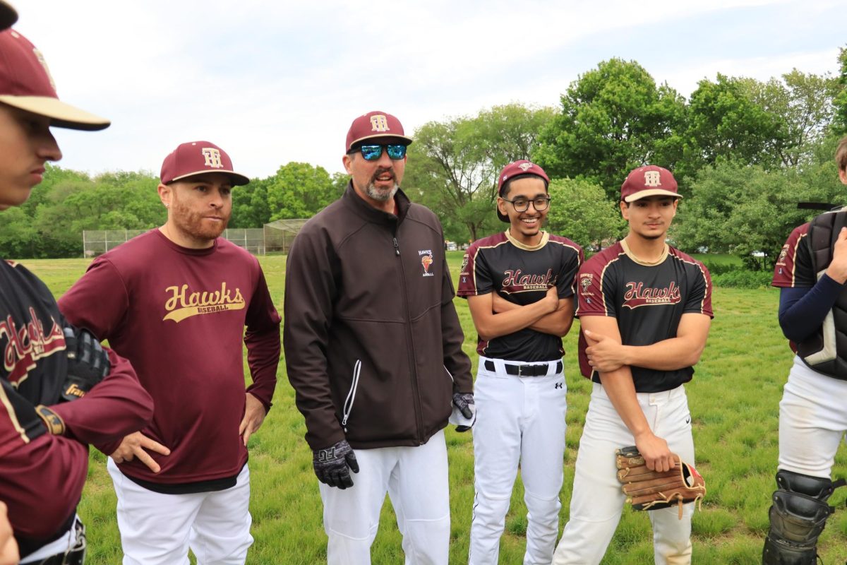 Coaches Richard Rodriguez and Matthew Lemanczyk talking to the boys varsity baseball team during a huddle. The team celebrated Senior Day and competed against Queens High School of Teaching on May 14, earning a 15-5 victory for the last game of the regular season.