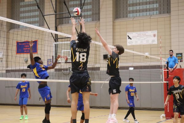 Junior Yousef Razzao and sophomore Jack Hill jump up to block the opposing hitter from August Martin during the boys varsity volleyball game on April 28.